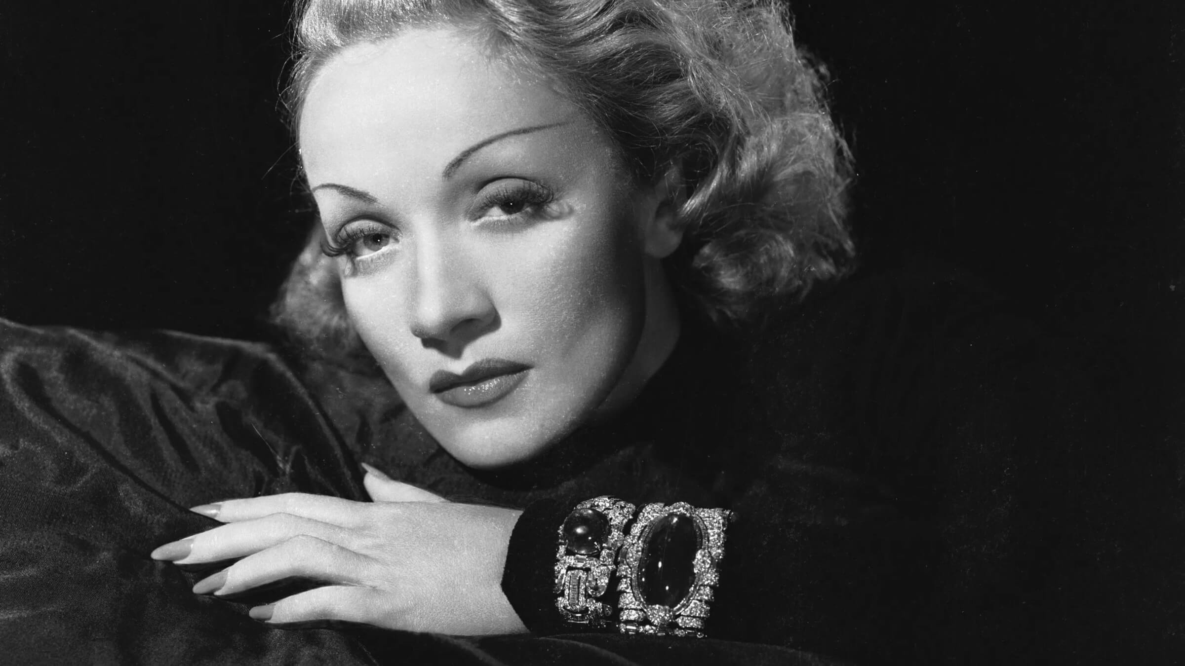 Marlène Dietrich wearing her Trabert & Hoeffer-Mauboussin emerald and diamond bracelet and emerald bracelet by Paul Flato